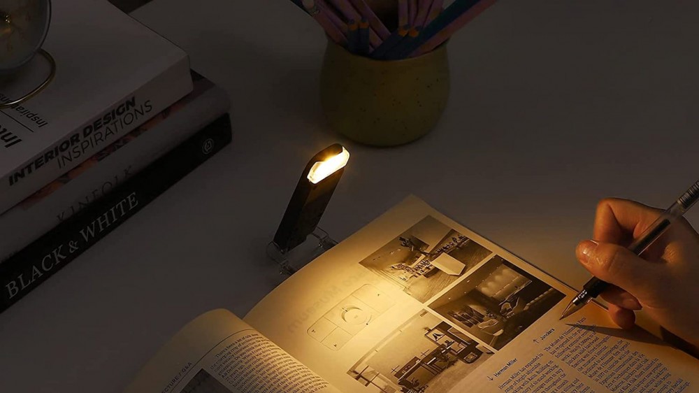 Dewenwils reading lamp attached to a book on a desk.